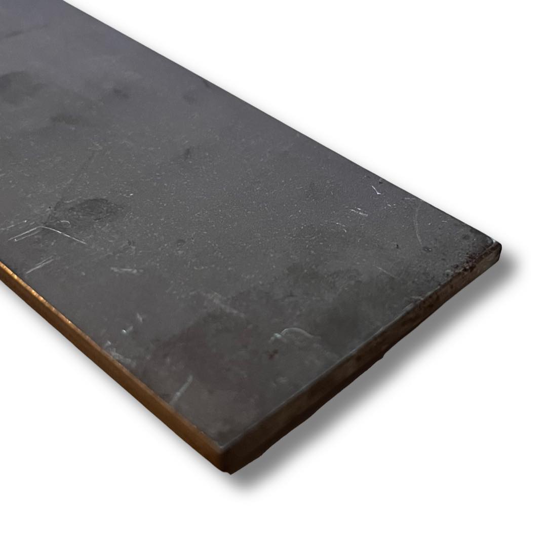 A close-up image of a black stainless steel knife blade with visible textures and markings, likely a product of Hitachi Aogami Blue 2.